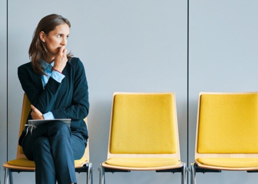 A woman anxiously waiting to be called for an interview.