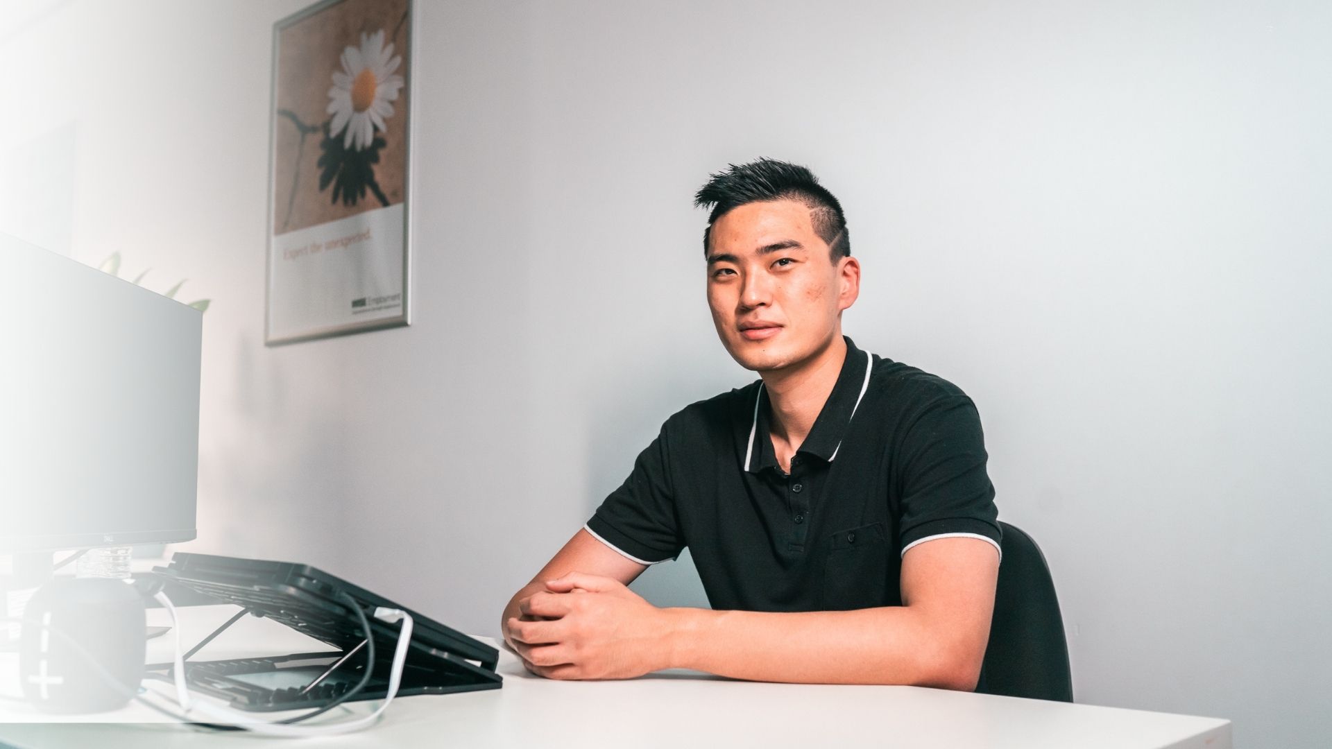 Image of John sitting at a desk and looking at the camera