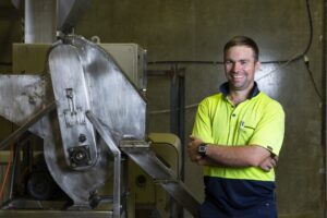 Smiling young man standing beside a machine.