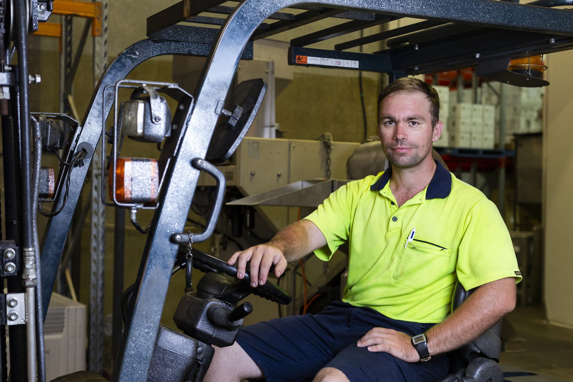 Smiling young man seated in a forklift.