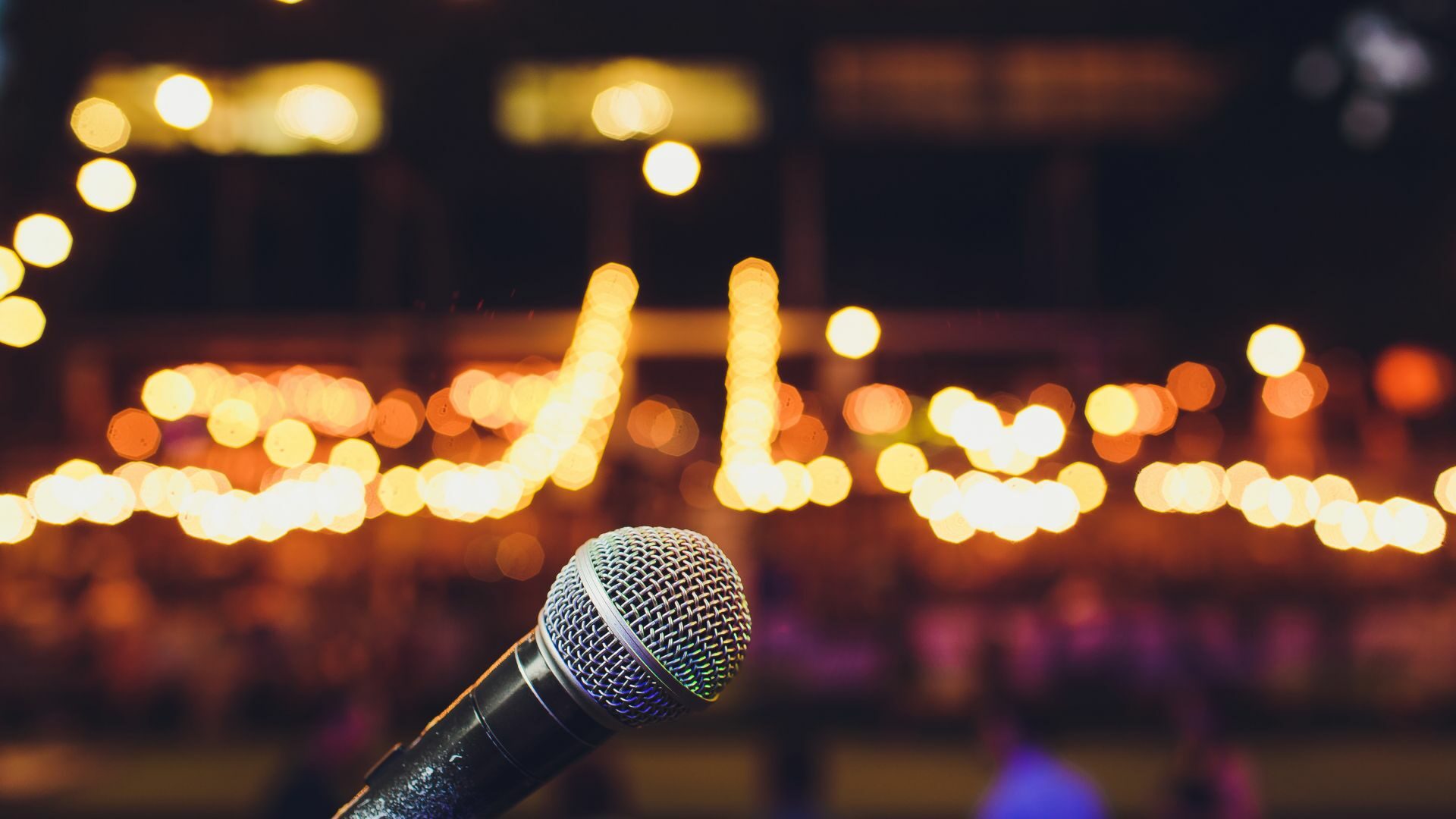Focus on a microphone with blurred lights in the background.