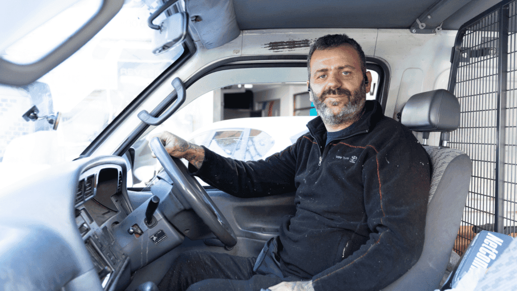 Abed sitting in van, holding the steering wheel
