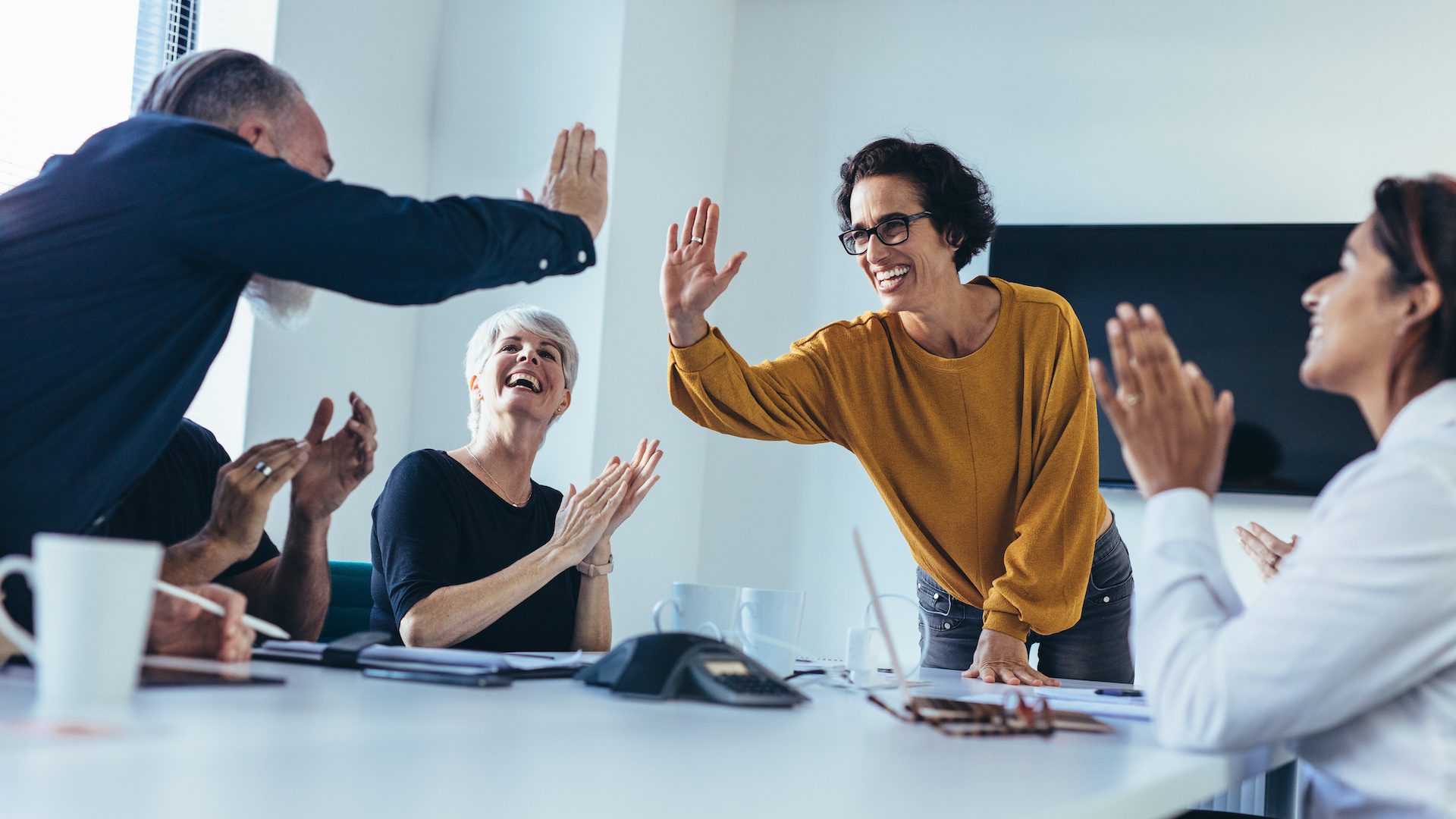 Business team celebrating success with high fives and clapping.