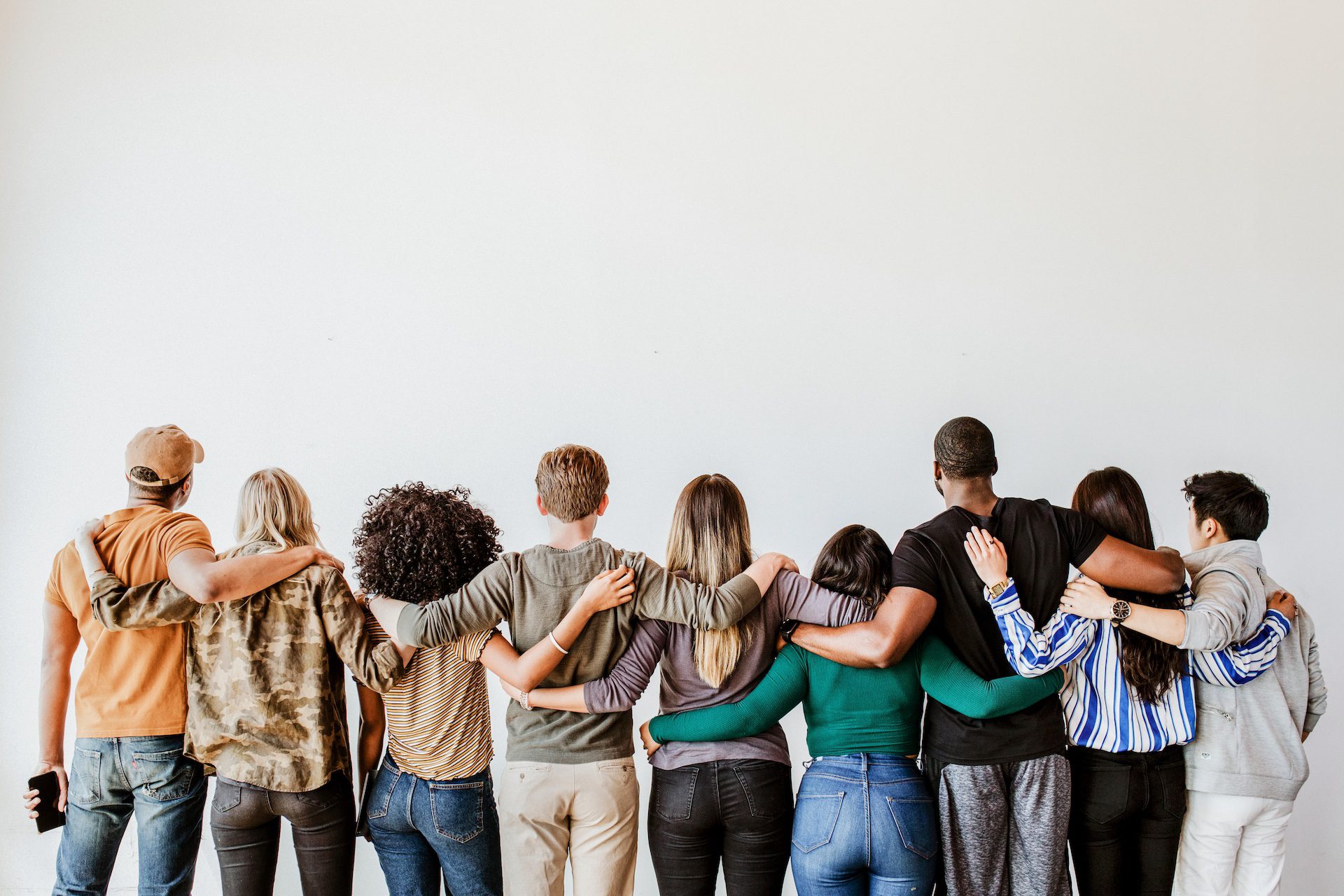 Rear view of diverse people hugging each other in a single line.