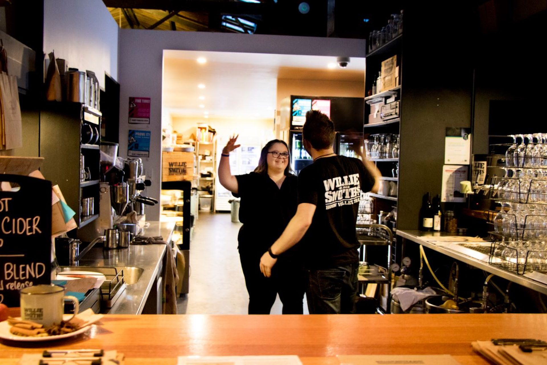 Young man and woman about to high five behind a restaurant counter.