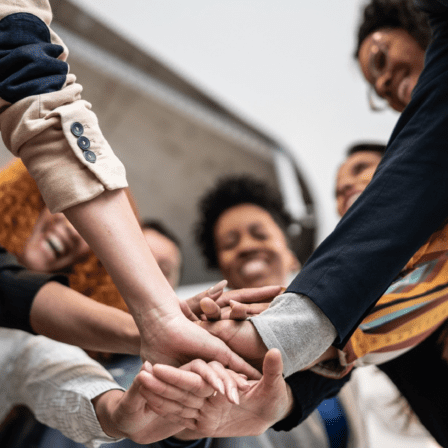 group of people putting their hands in the middle of a circle