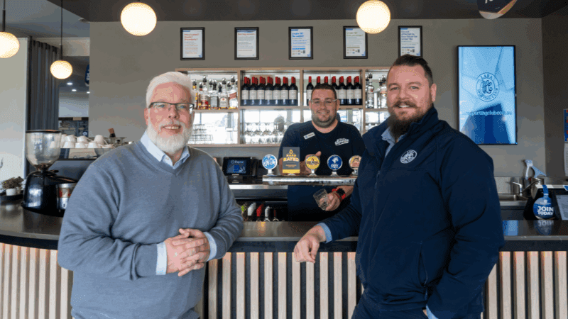 Paul from WISE and Brendon from Lara Sporting Club standing front of a bar with Shannon standing behind the drink taps of the bar
